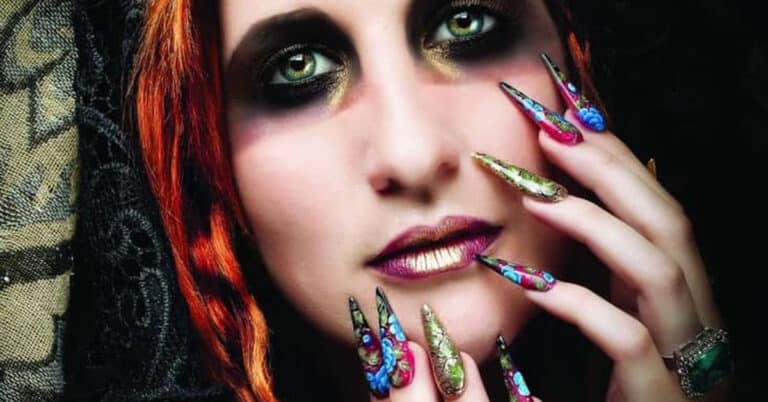 Model with dramatic eye makeup and purple nail art by student Samantha Fourie