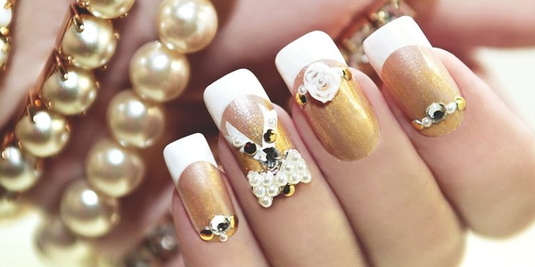 Gold and white builder gel nails decorated with pearls and gems