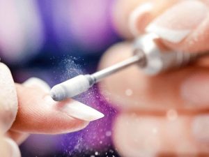 Electric nail file refining a pink nail extension