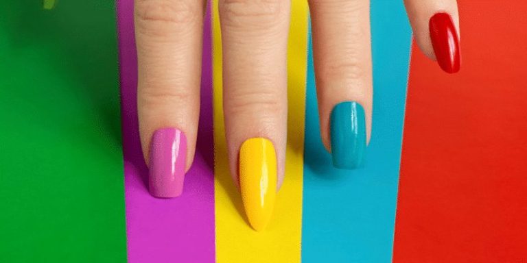 Shaped nails painted yellow, blue, green and red against a colourful background